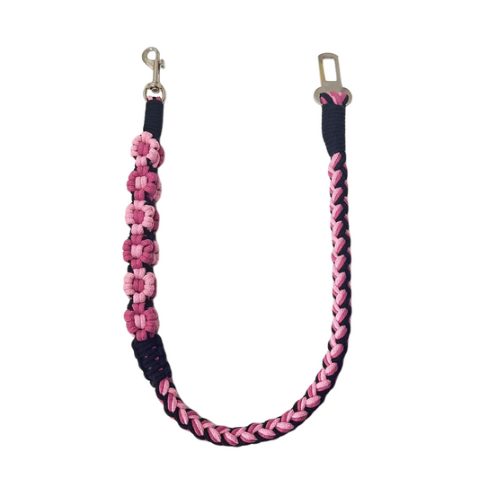 A handmade black and pink dog safety seatbelt featuring braided patterns and flower details, designed for durability and style.