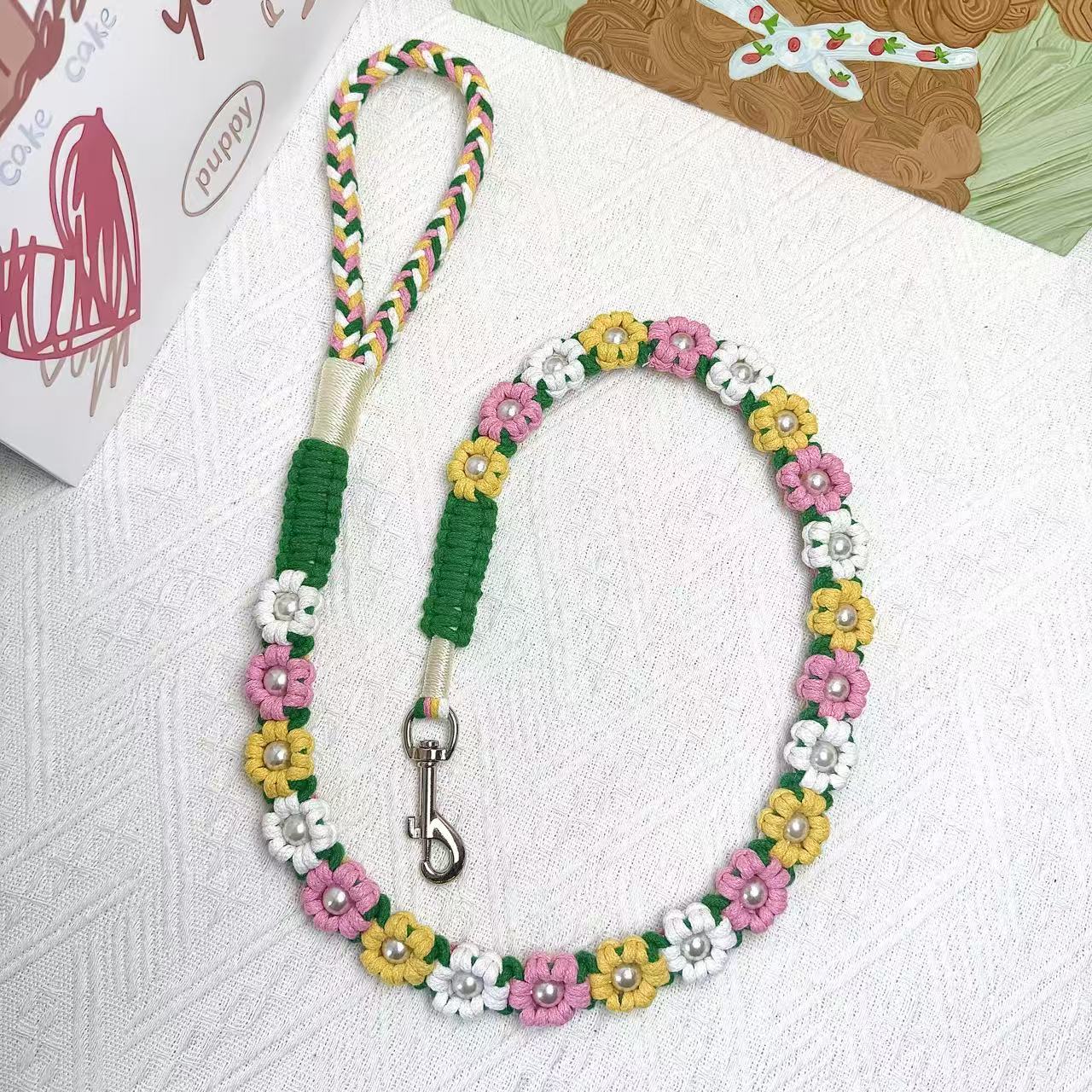 A white, yellow, and pink braided handmade dog leash laid flat in a circular arrangement, showcasing the durable handle and sturdy metal clip, ideal for daily walks.