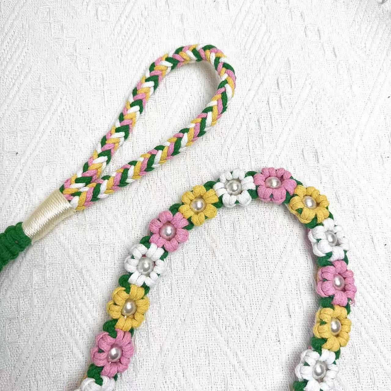 A detailed view of a blooming meadow handwoven dog leash with a charming floral design. The leash is elegantly placed on a textured white surface, highlighting its intricate craftsmanship and vibrant colors.