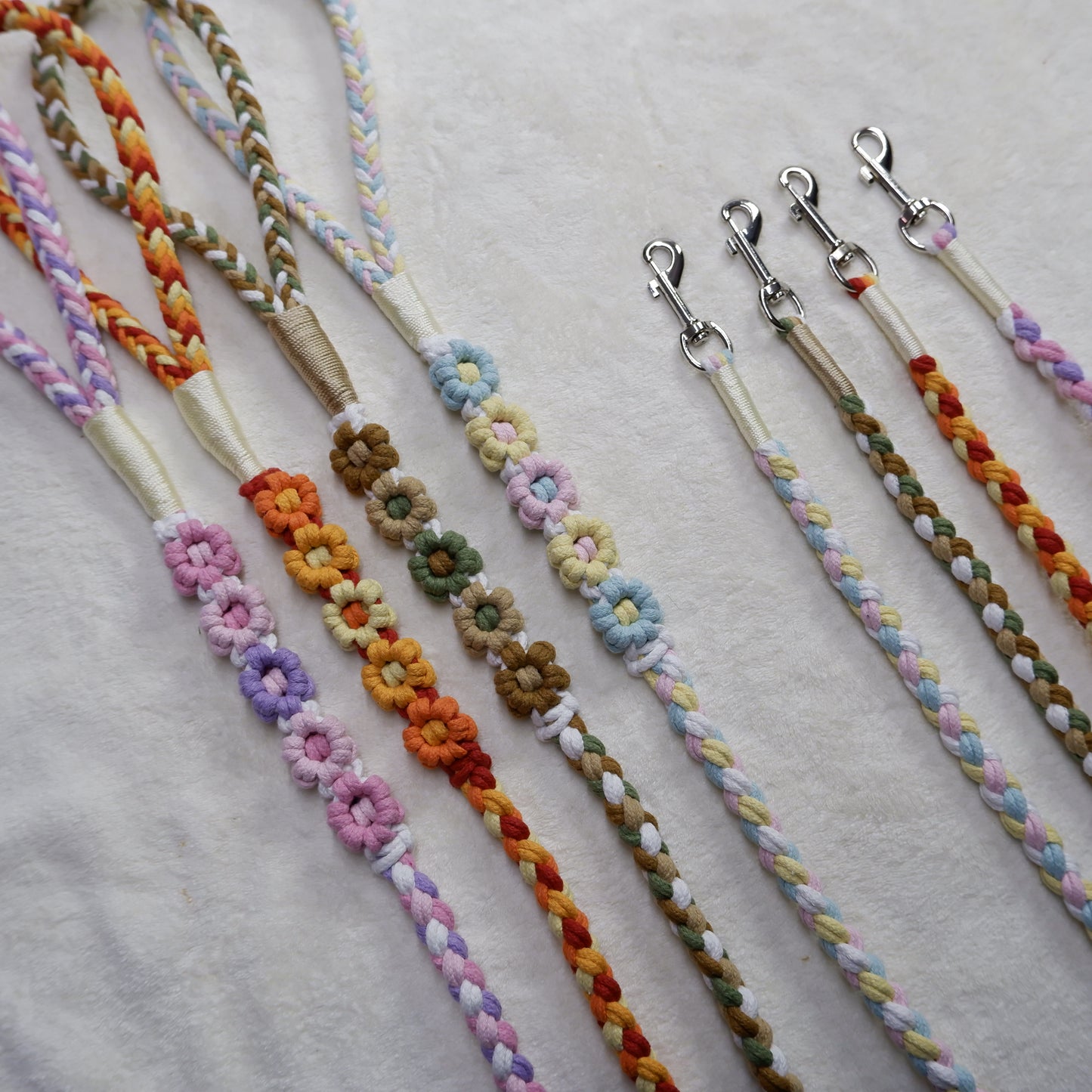 Four lively handmade dog leashes showcasing colorful braided handles, durable clips, and intricately woven floral details, ideal for everyday walks.