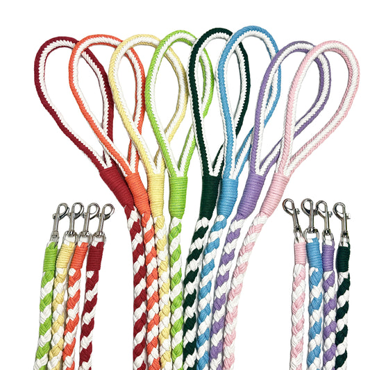 A collection of vibrant handwoven braided dog leashes in multiple colors, featuring durable cotton rope with sturdy metal clips. The leashes have looped handles for a comfortable grip and a stylish twisted design.