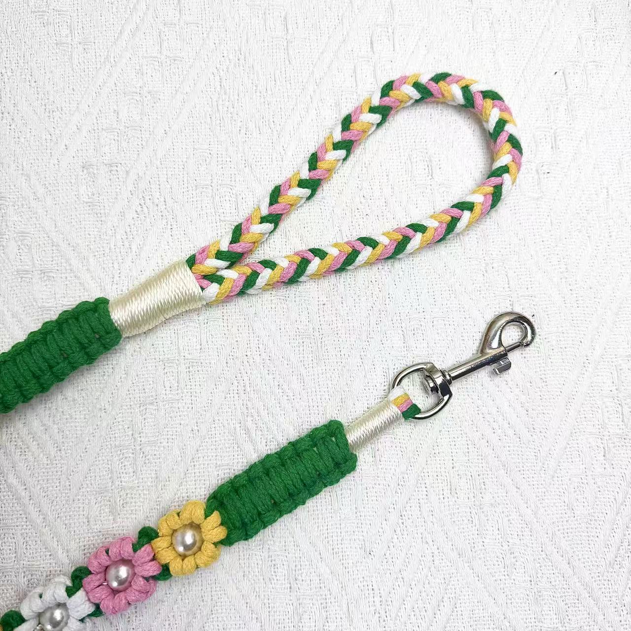 The soft handle and the clip of the handmade blooming meadow dog leash, featuring multiple beautiful woven flowers.