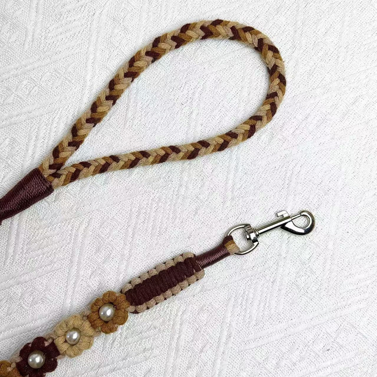 The soft handle and the clip of the handmade gradient brown dog leash, featuring multiple beautiful woven flowers.