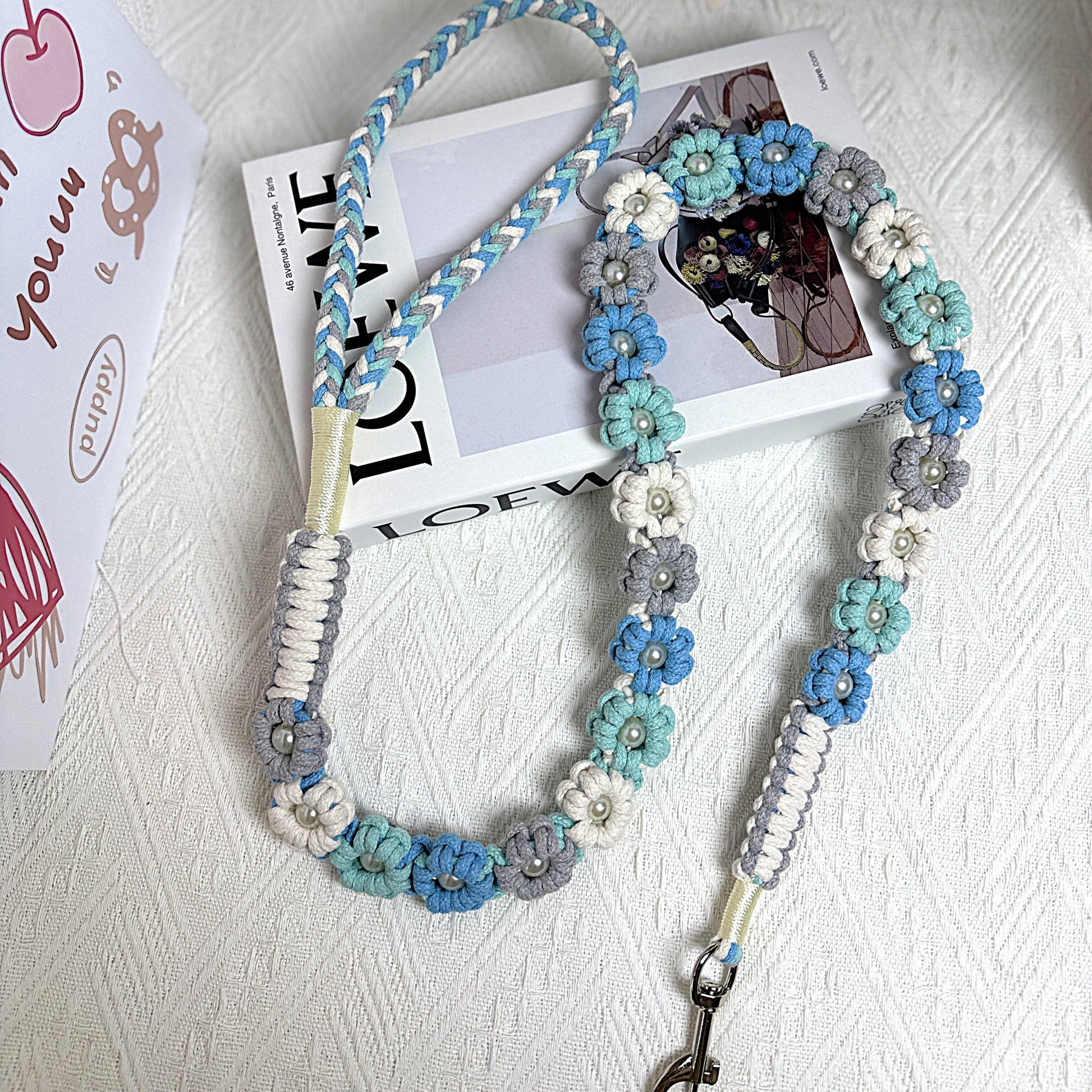 The soft handle and the clip of the handmade ocean blue dog leash, featuring multiple beautiful woven flowers.
