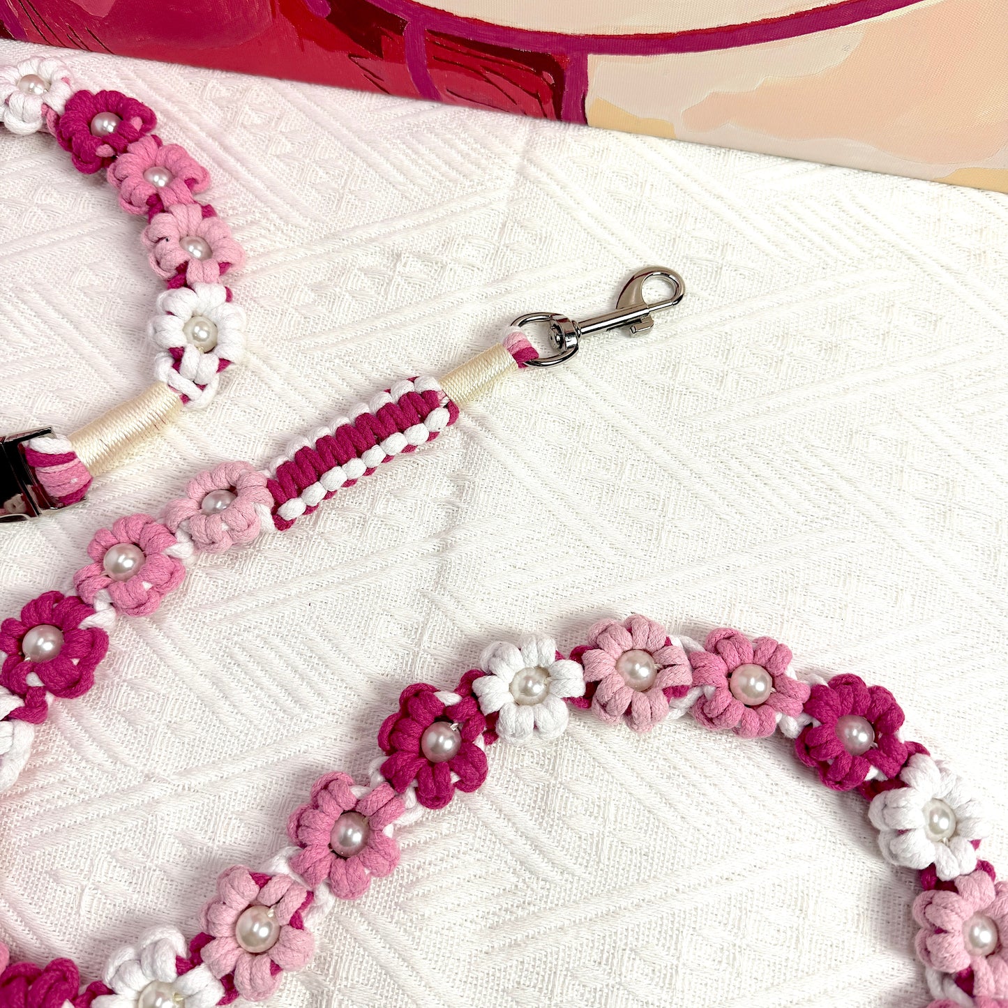 The clip of the handmade pink white dog leash, featuring multiple beautiful woven flowers.