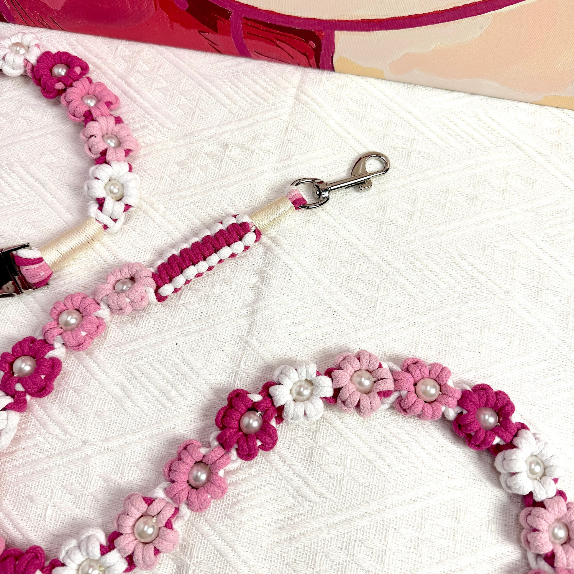 The clip of the handmade pink white dog leash, featuring multiple beautiful woven flowers.