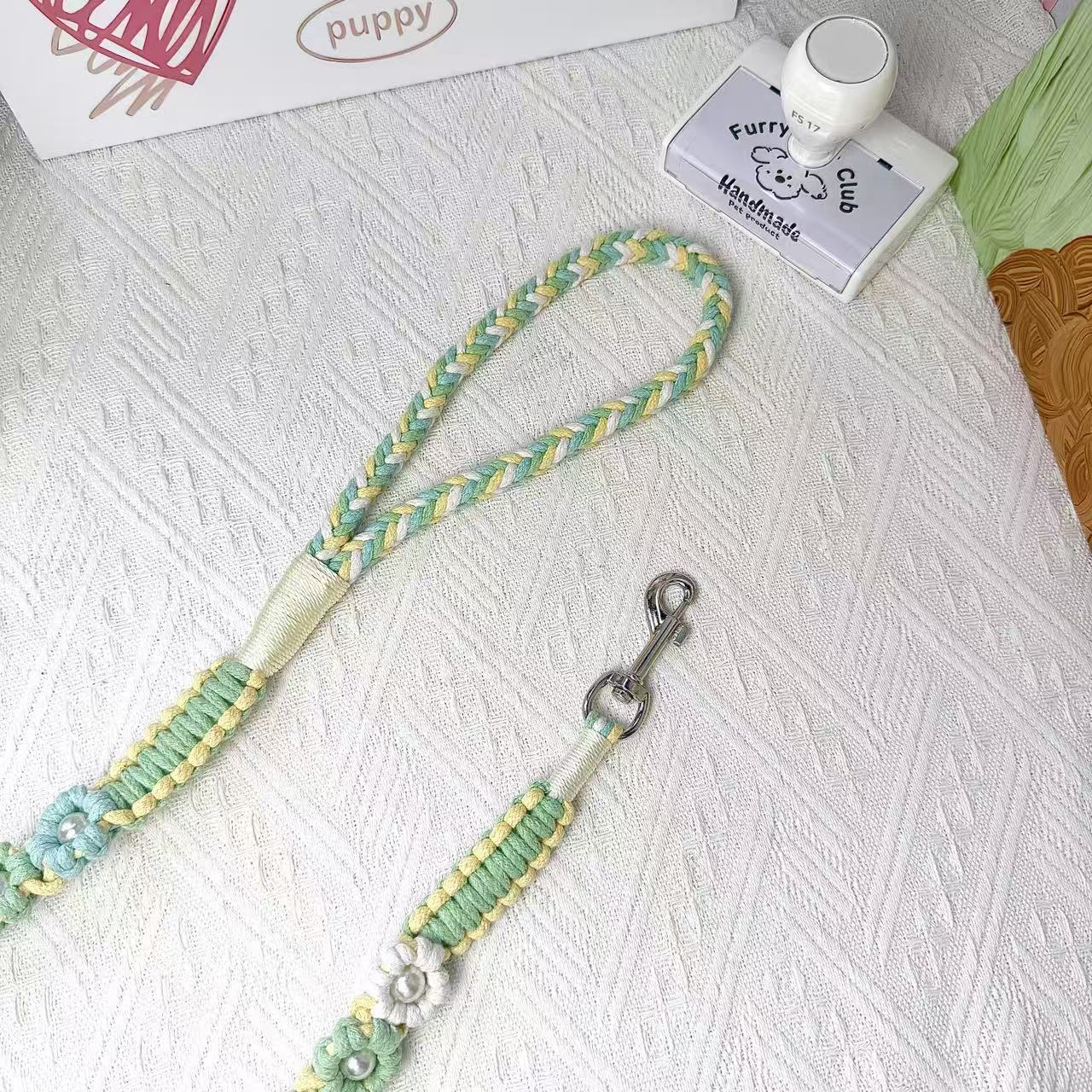 The soft handle and the clip of the handmade spring mint dog leash, featuring multiple beautiful woven flowers.