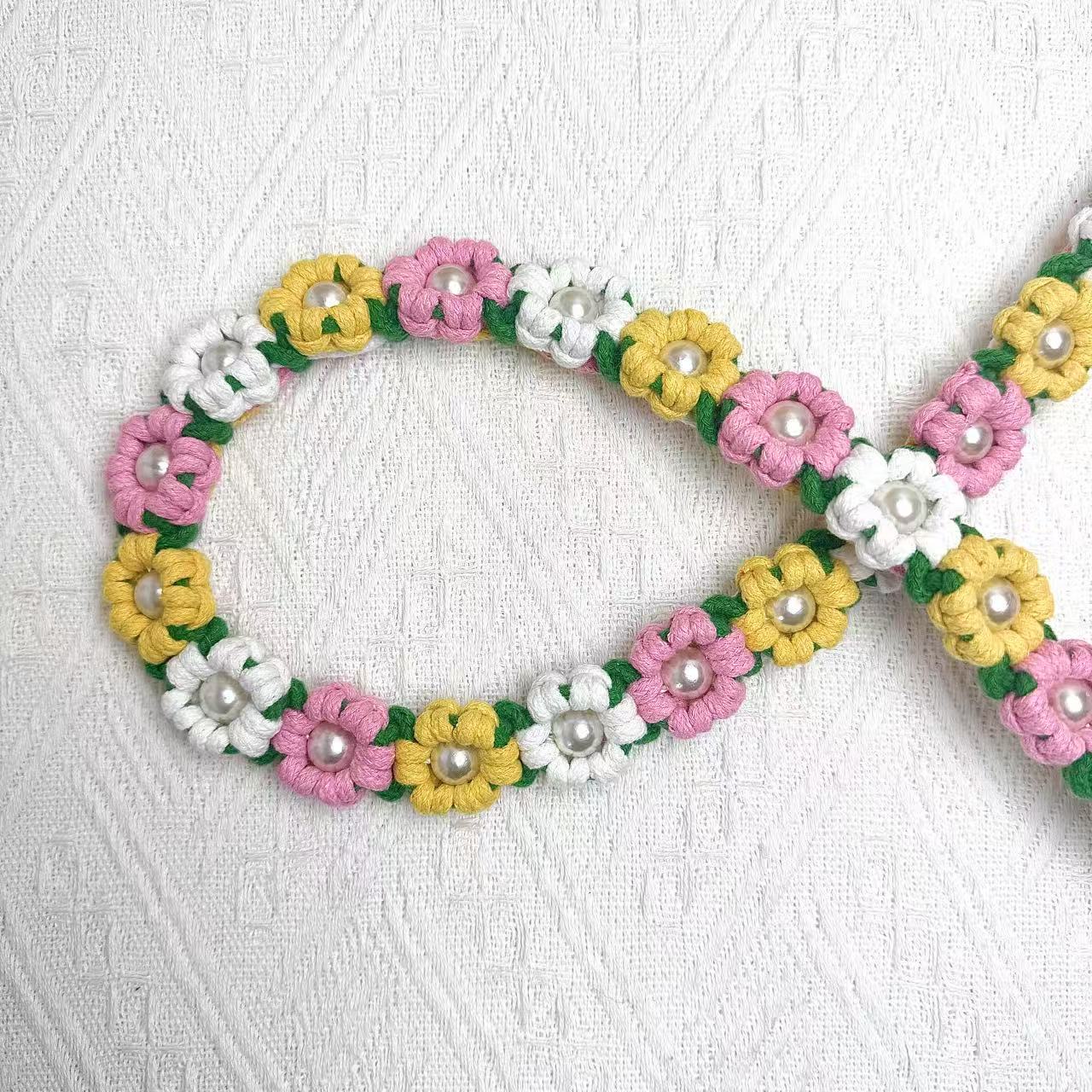 Dog leash decorated with numerous handcrafted flowers in vibrant yellow, pink, and white tones.