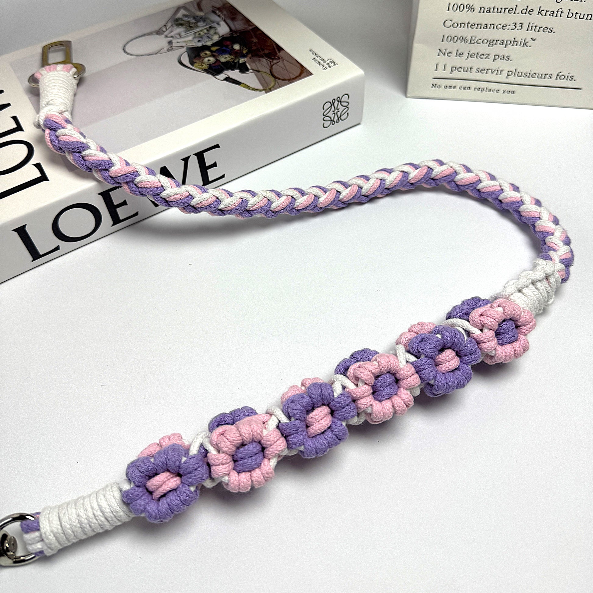 Dog seatbelt decorated with numerous handcrafted flowers in bright purple and pink tones.