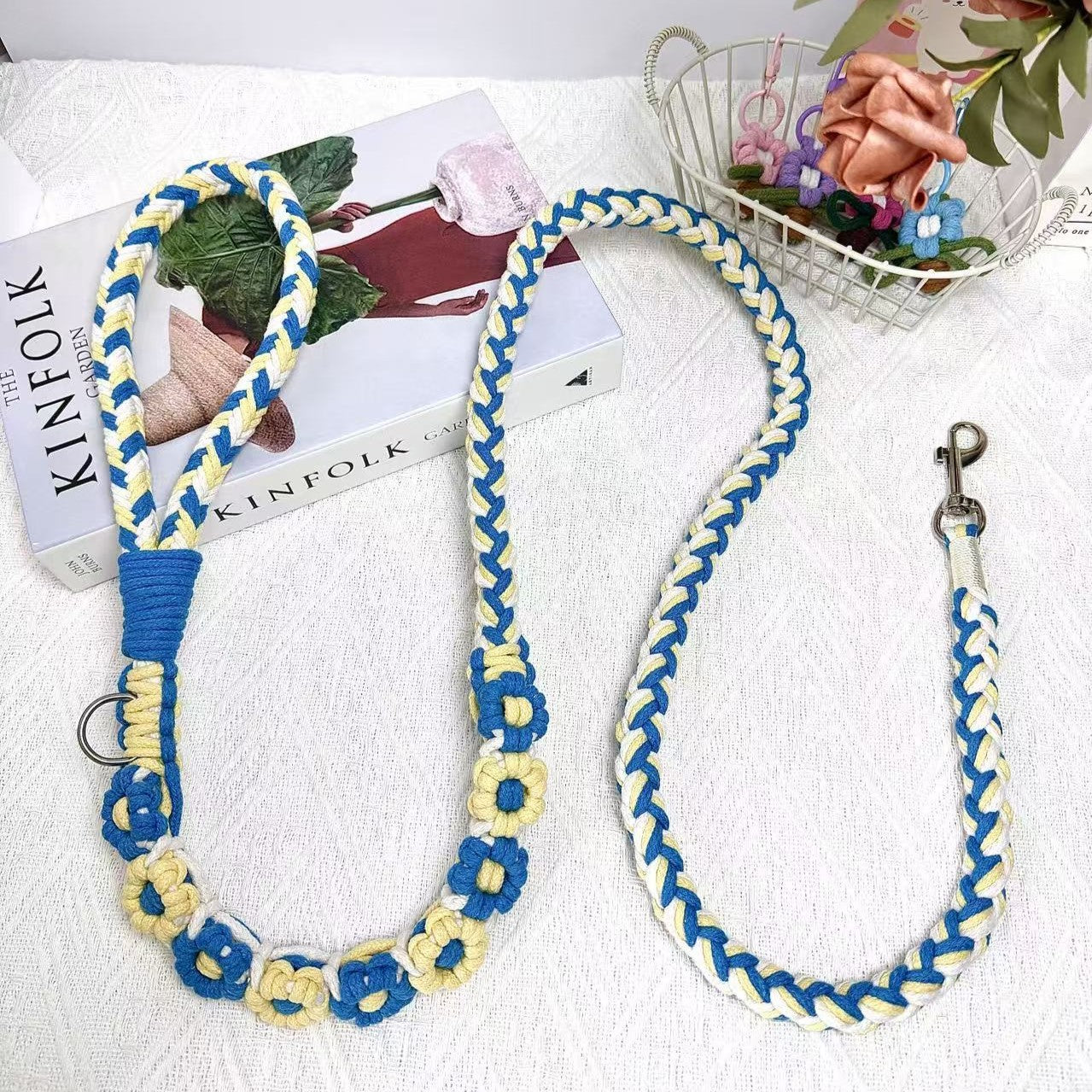 A beautifully handwoven blue and yellow dog leash featuring a sturdy loop handle and a metal clip for secure attachment, displayed on a white surface with decorative elements.
