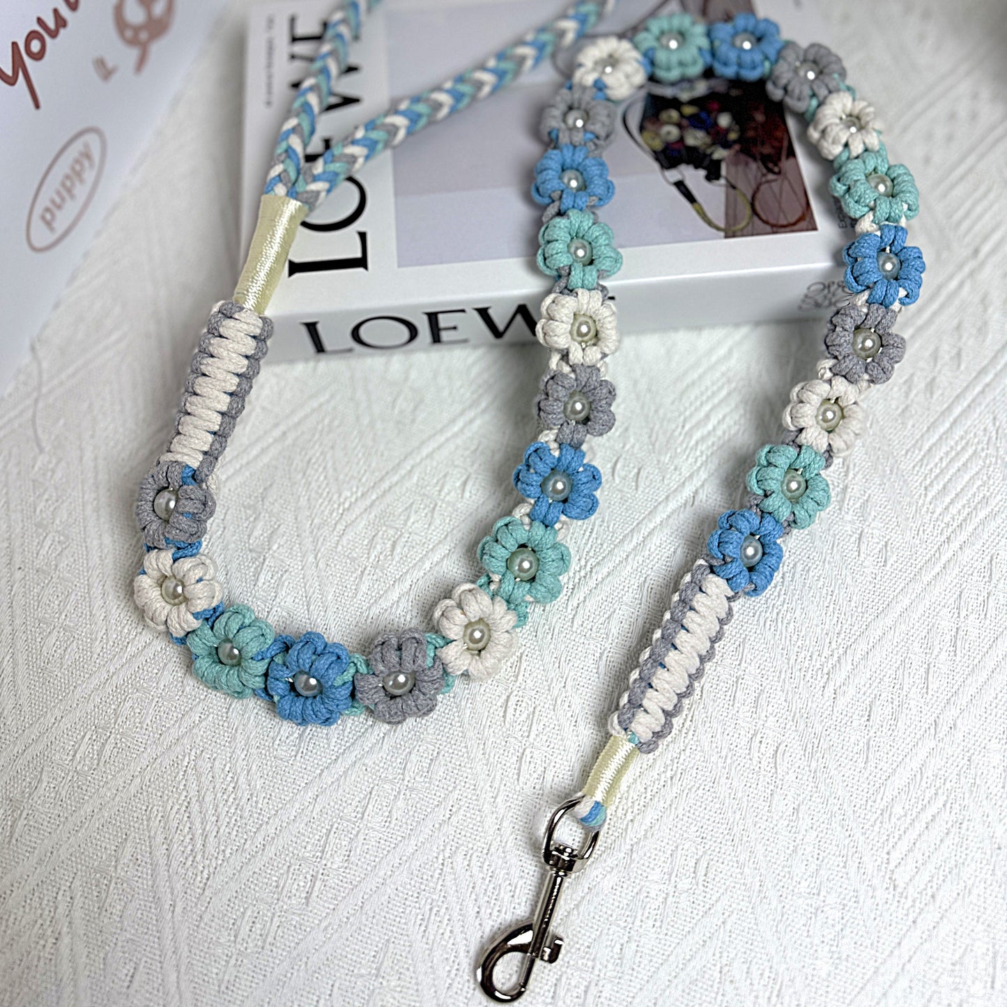 The soft handle and the clip of the handmade ocean blue dog leash, featuring multiple beautiful woven flowers.