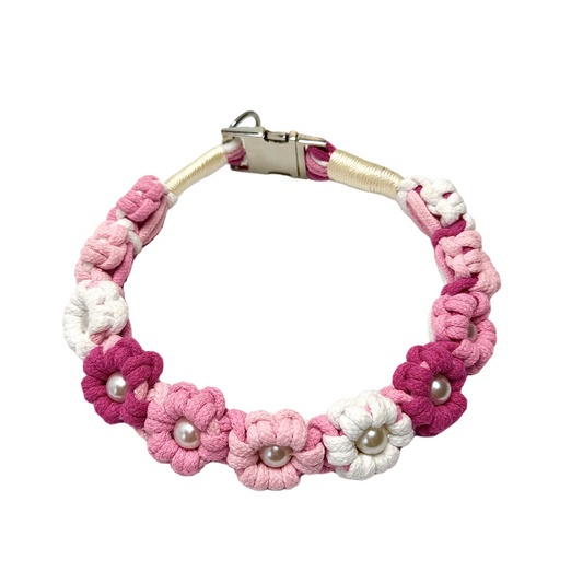 A pink and white handmade dog collar featuring braided flower patterns with pearl embellishments, adding a touch of elegance to your pet's life.