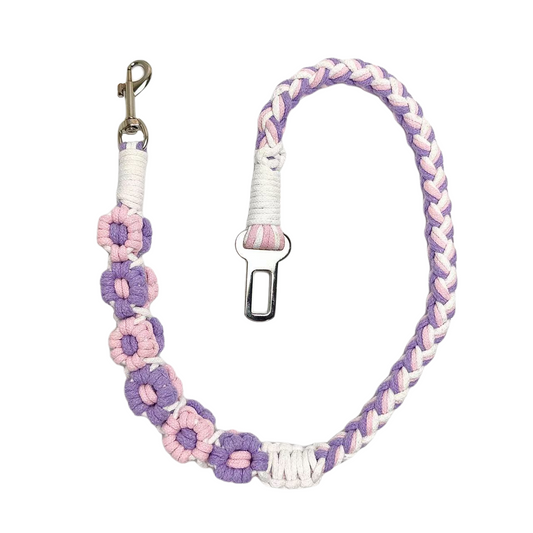 A handmade purple, pink, and white dog safety seatbelt featuring braided patterns and flower details, designed for durability and style.