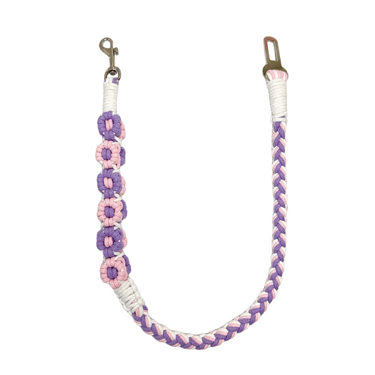 A handmade purple, pink, and white dog safety seatbelt featuring braided patterns and flower details, designed for durability and style.