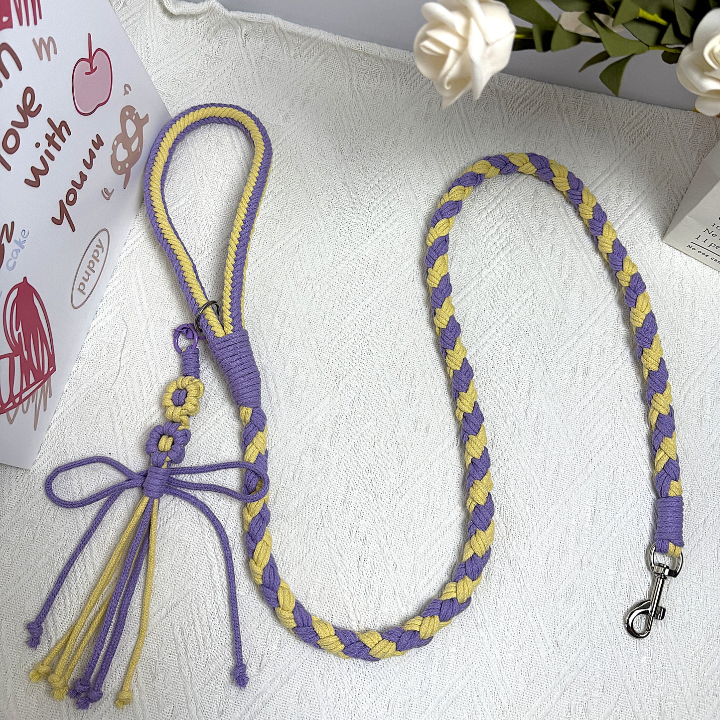 A purple and yellow braided handmade dog leash laid flat, showcasing the durable handle and sturdy metal clip, ideal for daily walks.