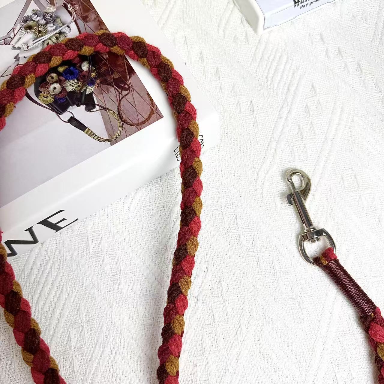 A close-up of a red and brown handwoven dog leash, showcasing the durable braided design and a polished metal clip for secure attachment.