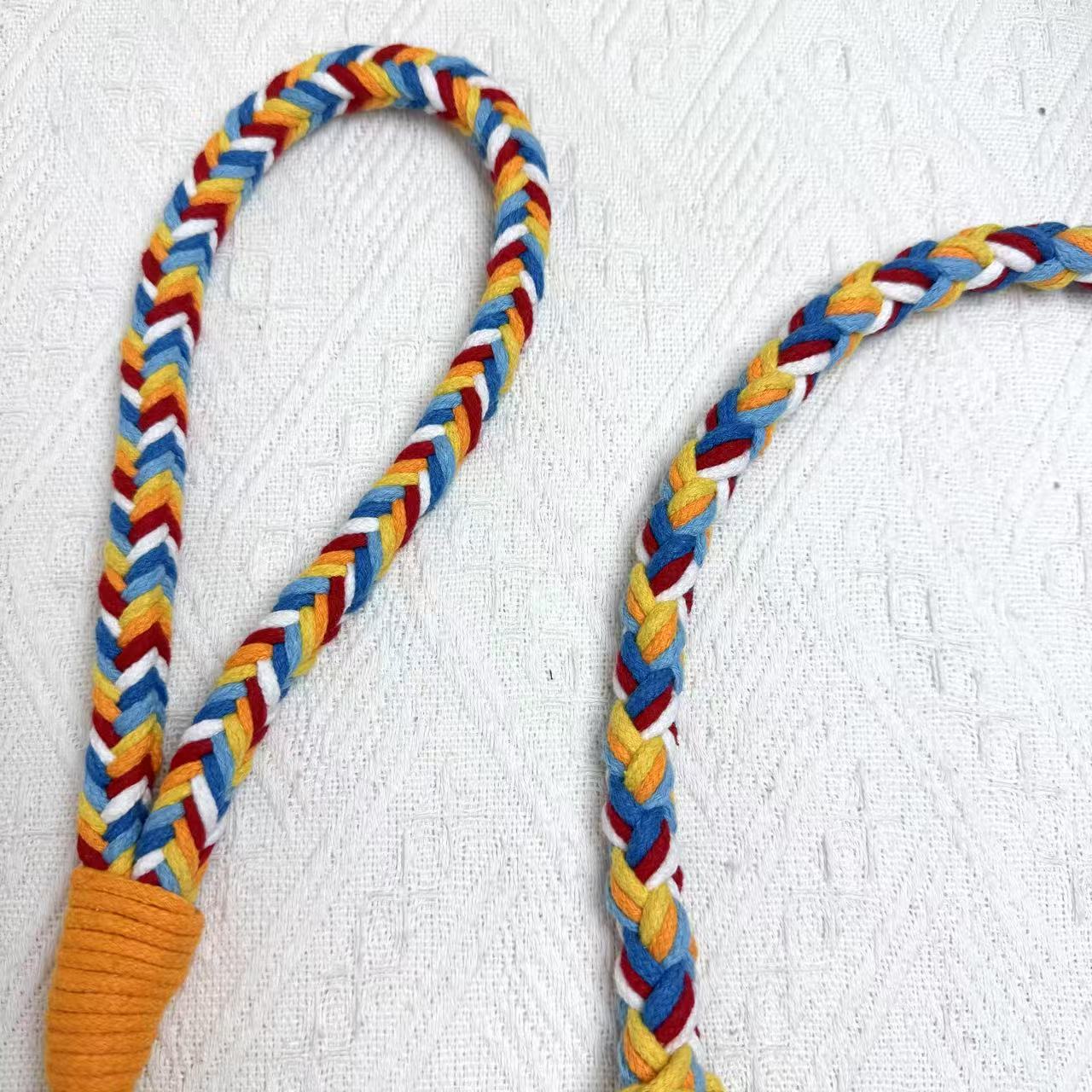 A detailed view of a red, blue, and orange braided dog leash, highlighting its sturdy handwoven handle section and the neatly arranged leash cord.