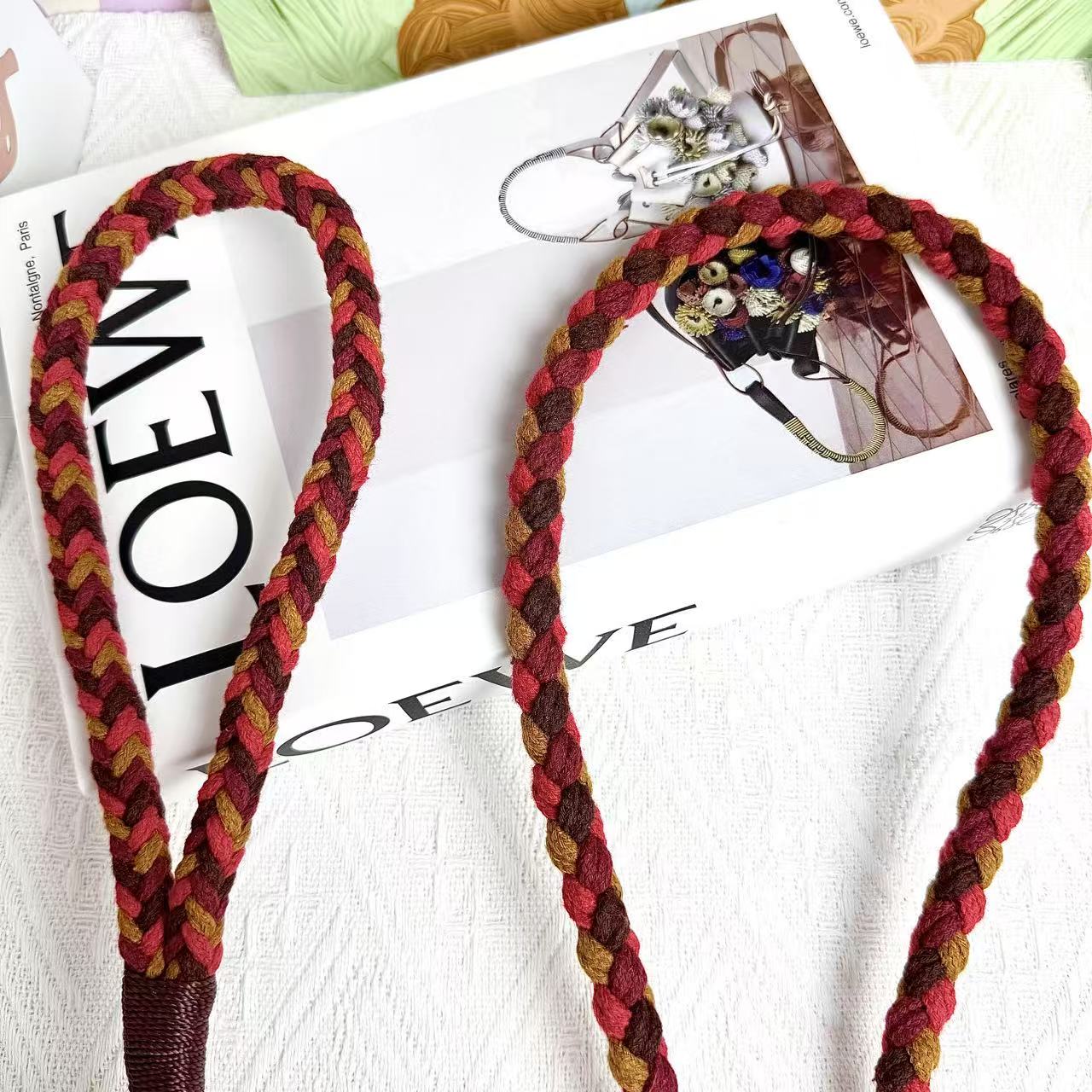 A detailed view of a red and brown braided dog leash, highlighting its sturdy handwoven handle section and the neatly arranged leash cord.