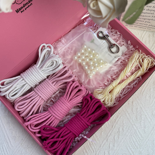 DIY dog leash kit featuring pink-toned cotton ropes, ice silk cords, a bag of pearls, one sewing kit, and a stainless steel clasp, neatly arranged in a pink box with decorative shredded paper.