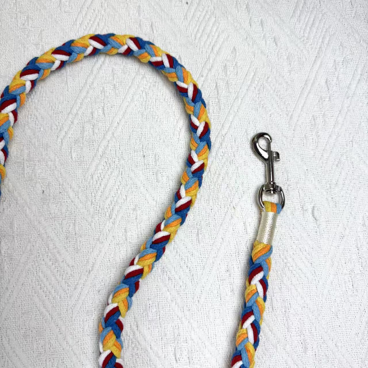 A close-up of a red, blue, and orange handwoven dog leash, showcasing the durable braided design and a polished metal clip for secure attachment.
