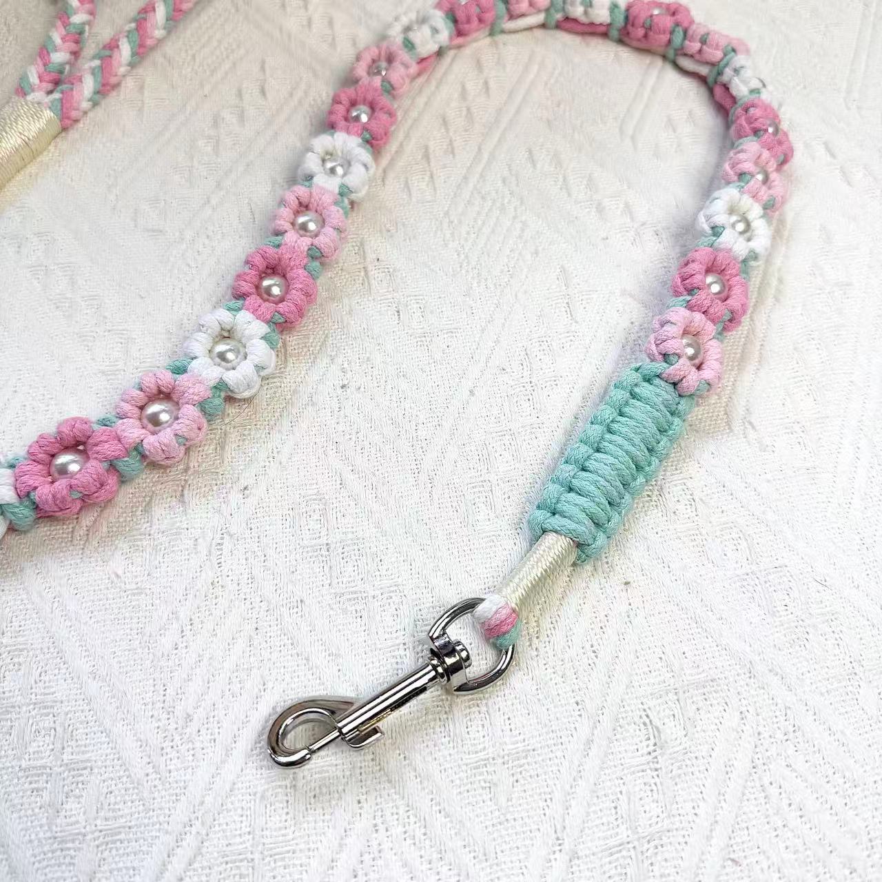 A close-up of a pink, light blue, and white handwoven dog leash, showcasing the durable braided design and a polished metal clip for secure attachment.