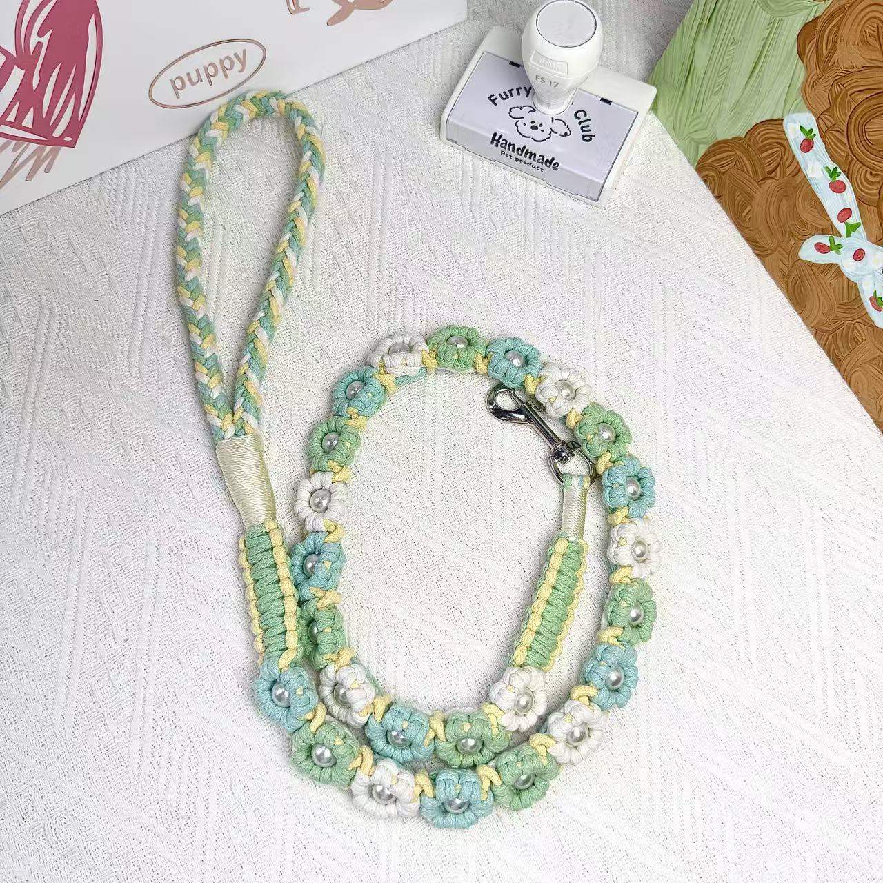A mint green and yellow braided handmade dog leash laid flat in a circular arrangement, showcasing the durable handle and sturdy metal clip, ideal for daily walks.
